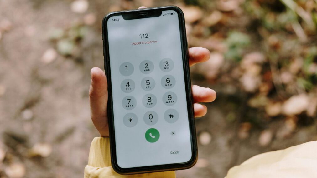 Close-up of emergency number dialed on smartphone held outdoors, emphasizing mobile technology's role in safety.